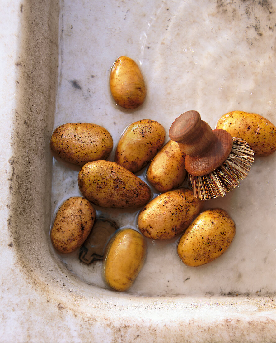 Potatoes with brush in rustic bowl
