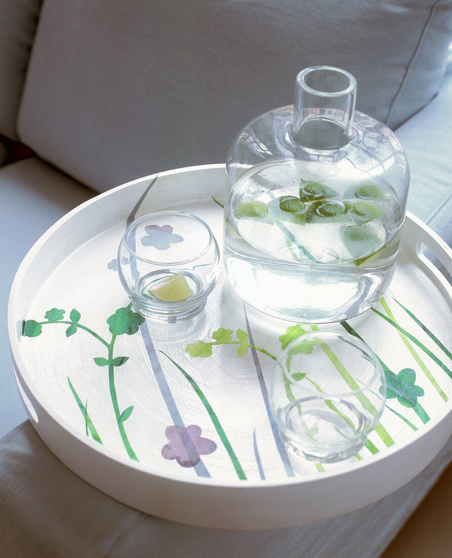 Glasses and carafe on tray printed with spring flowers meadow