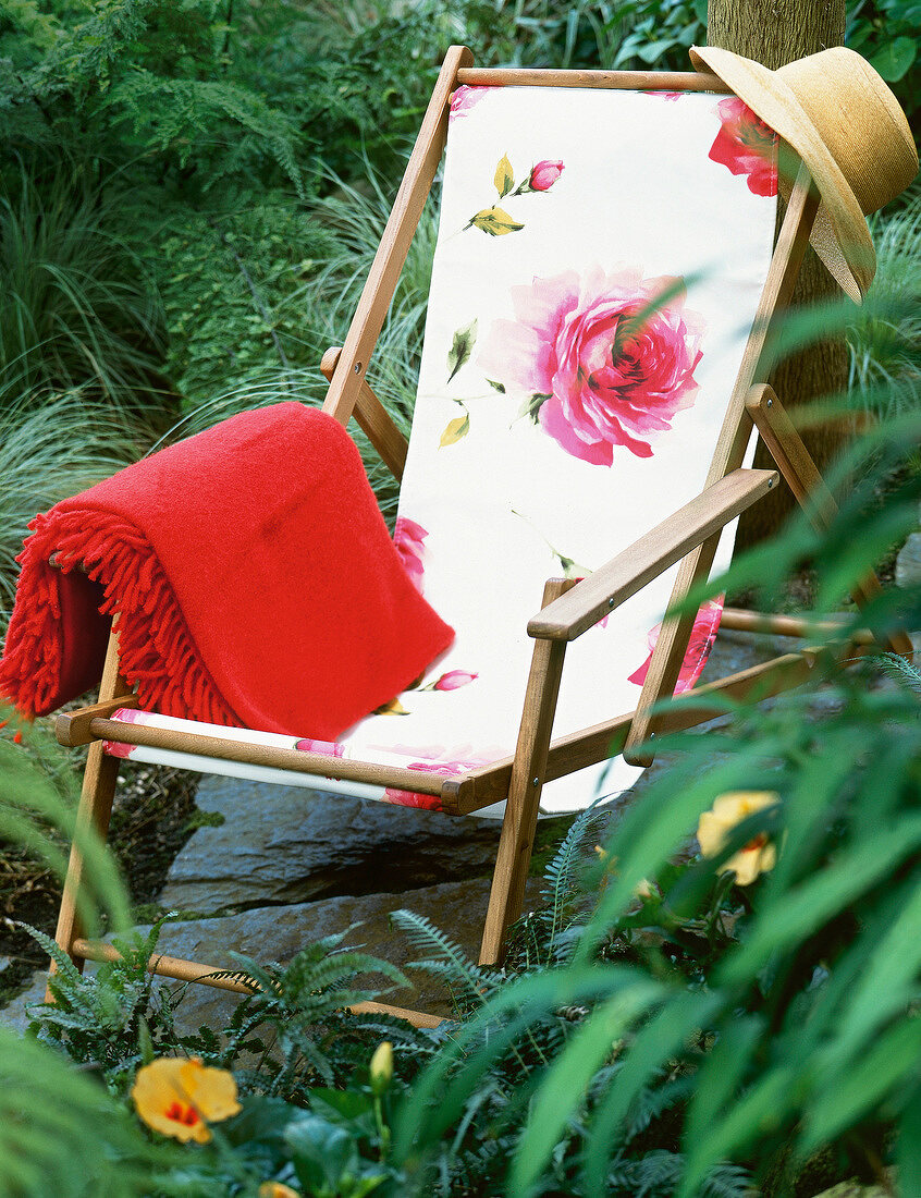 Empty lounge chair with rose patterned fabric lying in garden