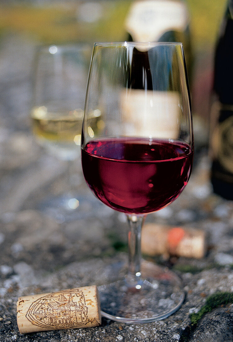 Glass of red wine from Switzerland with cork beside it