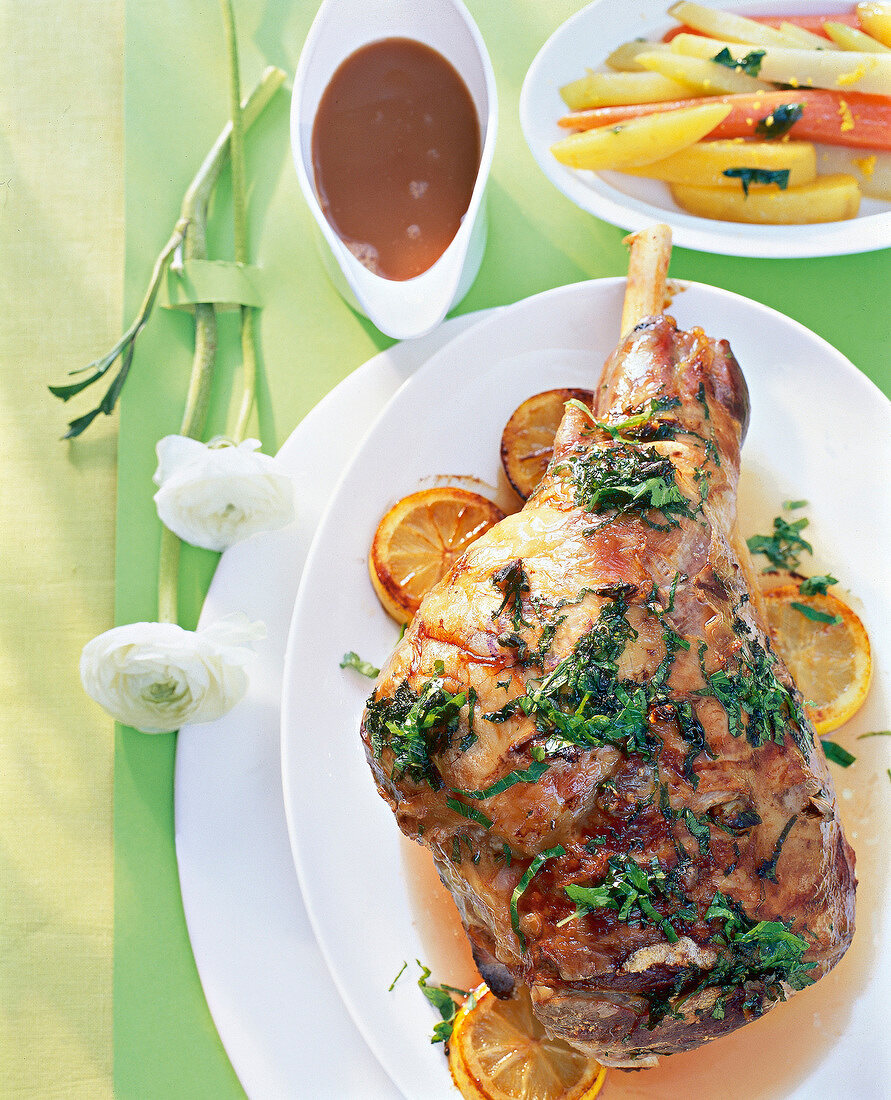 Close-up of roasted leg of lamb with potato and sage on plate