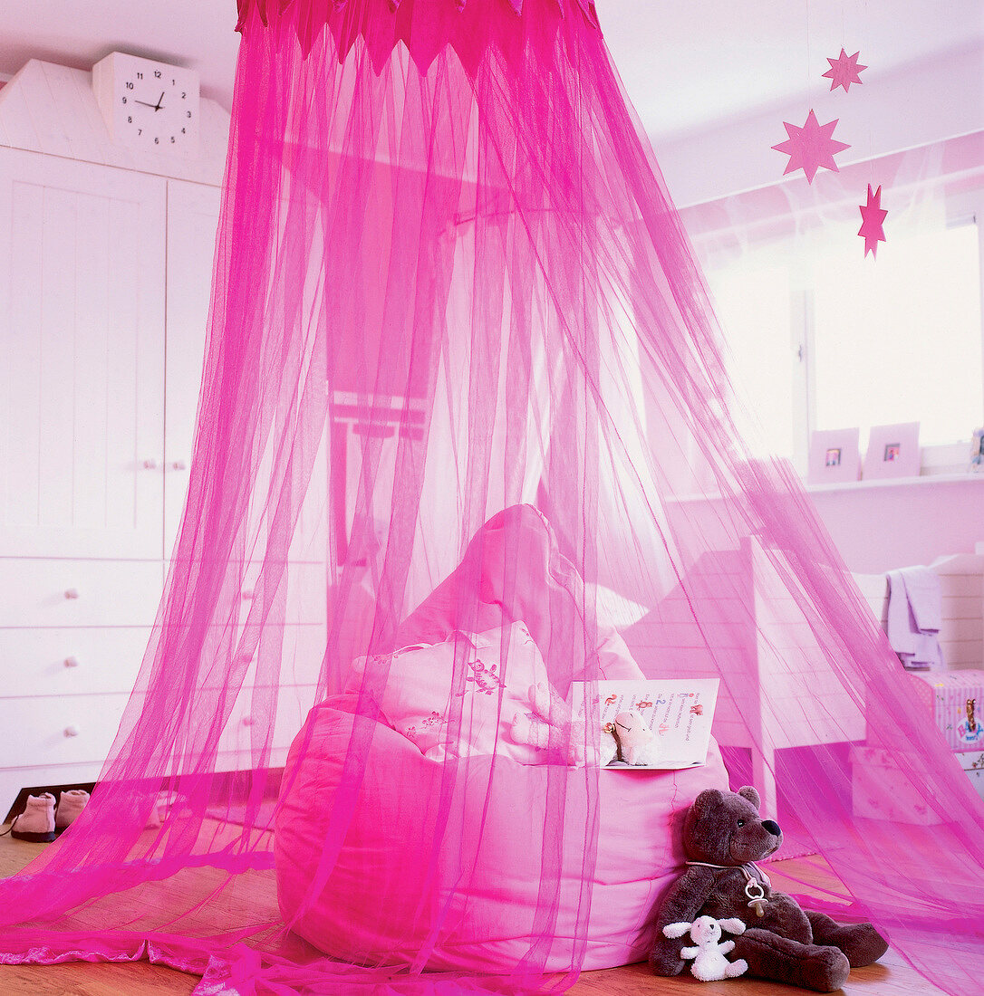 Pink beanbag inside pink tulle himmel in children room