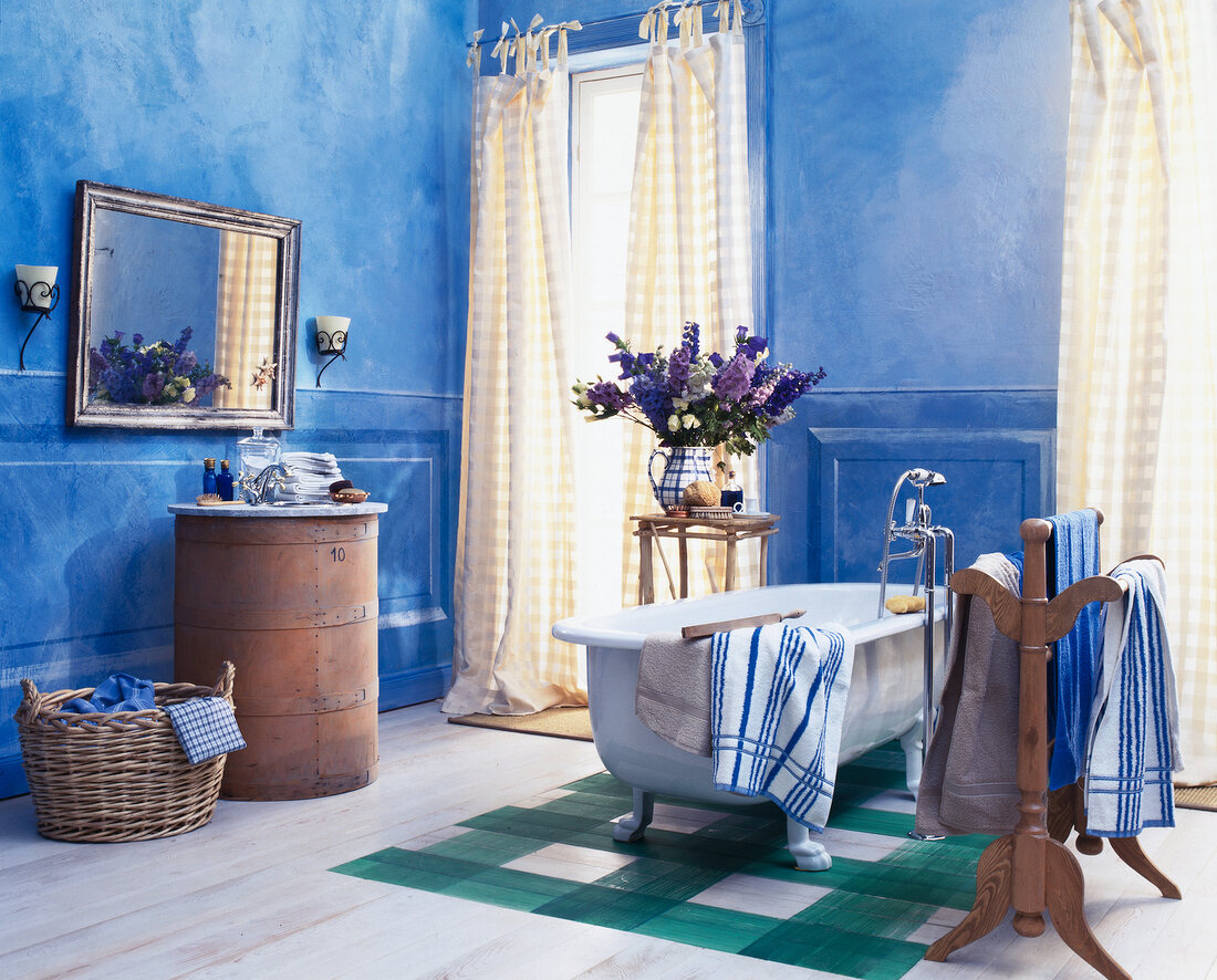 Bathroom with blue walls, cream curtains and old bathtub