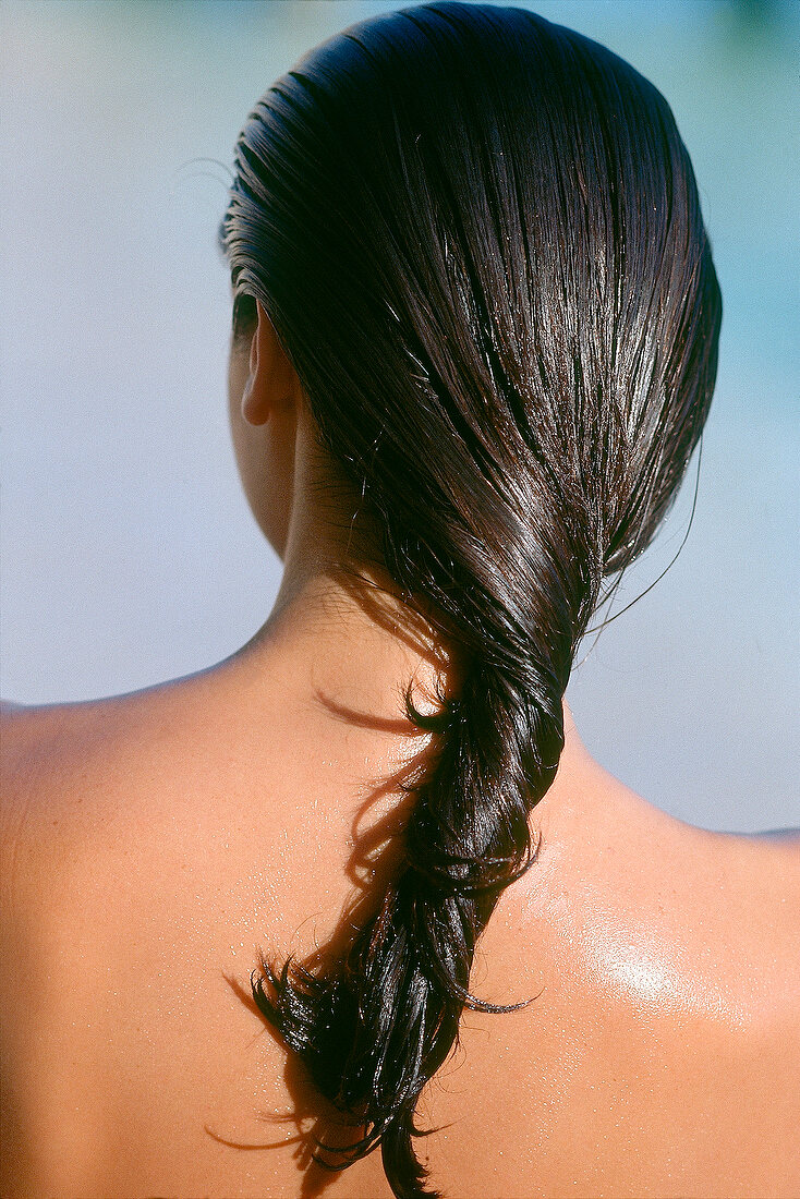 Rear view of woman applying conditioner after sunbathing