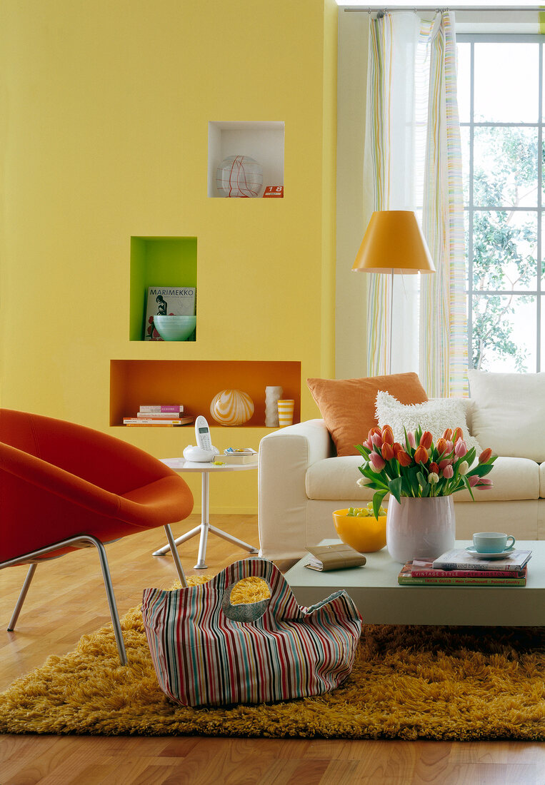 Living room in yellow with white sofa, orange armchair, table and floor lamp