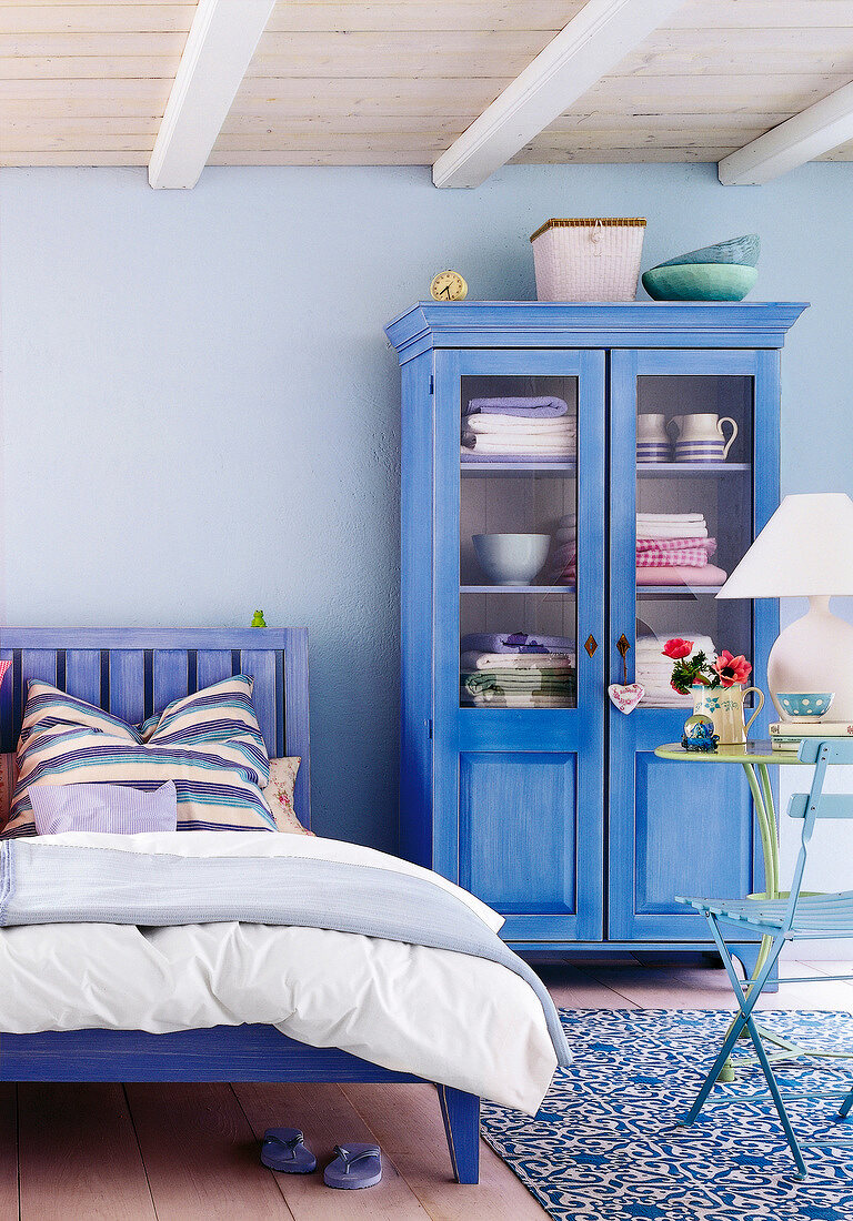 Rustic blue bed and wooden wardrobe in bedroom