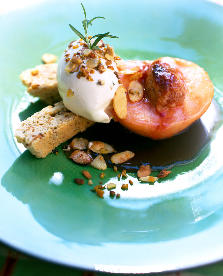 Close-up of glazed peach with almond ice cream and biscotti on plate