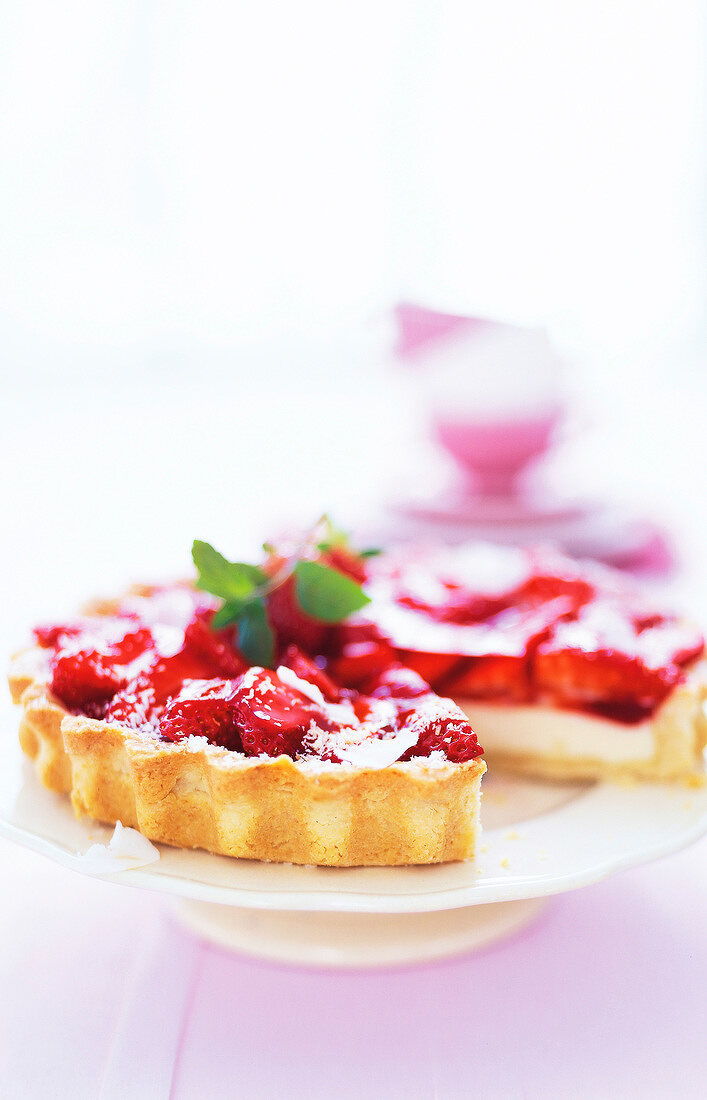 Strawberry cake garnished with coconut on cake stand