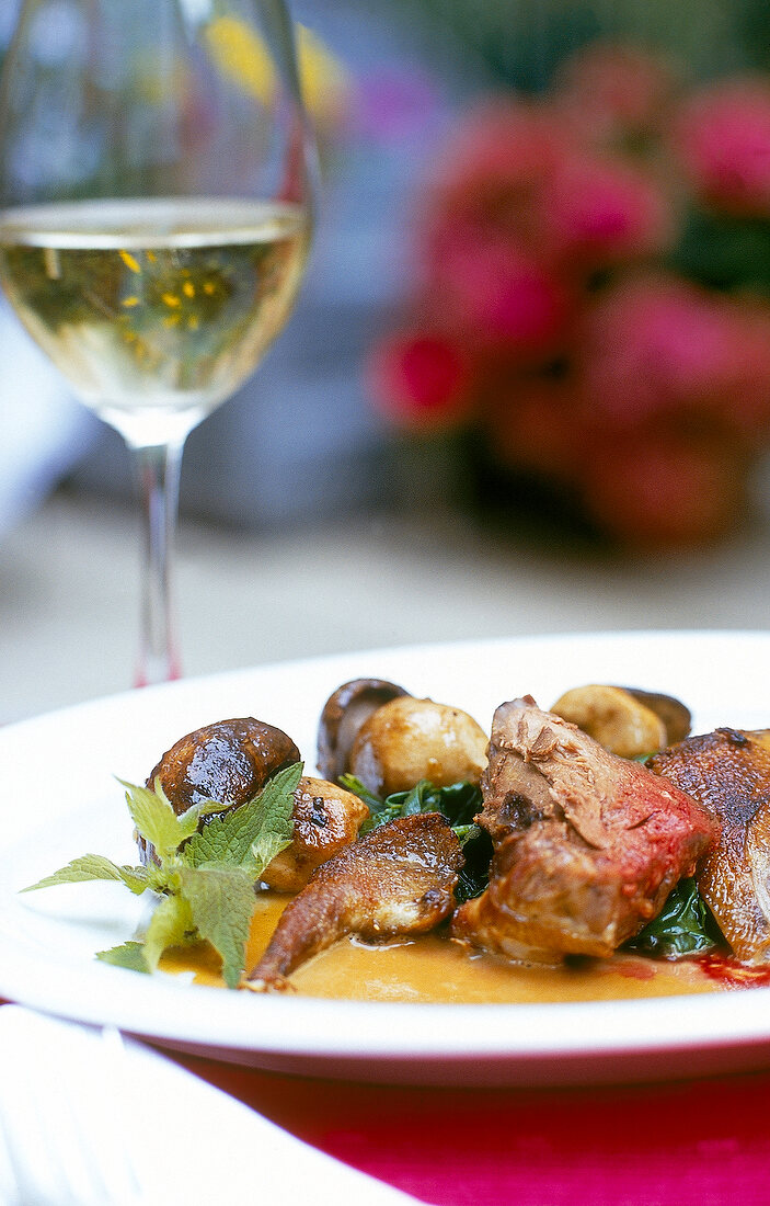 Braised pigeon with spinach mushrooms and nettles on plate