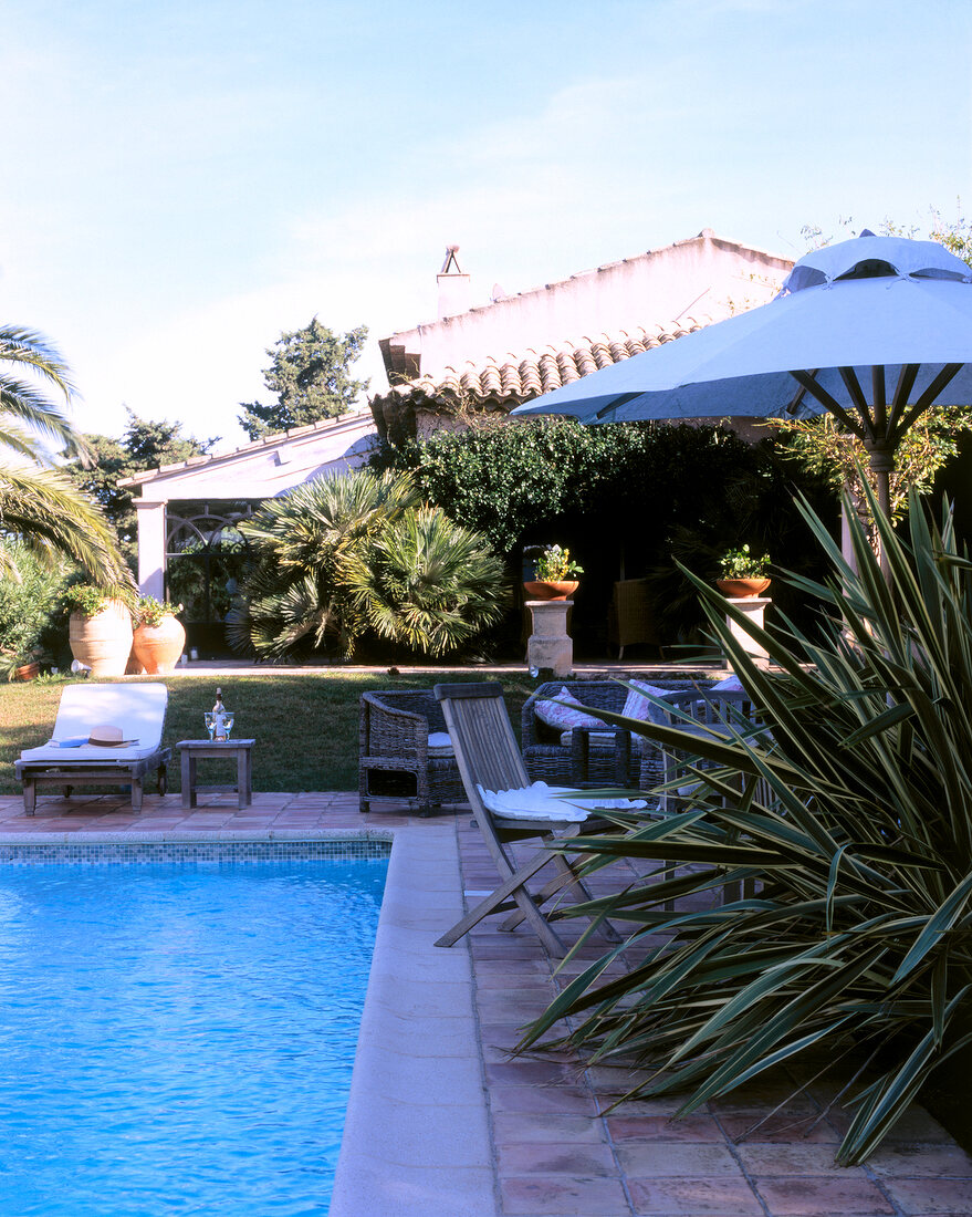 Sun loungers and wicker furniture at swimming pool of villa in Saint-Tropez, France