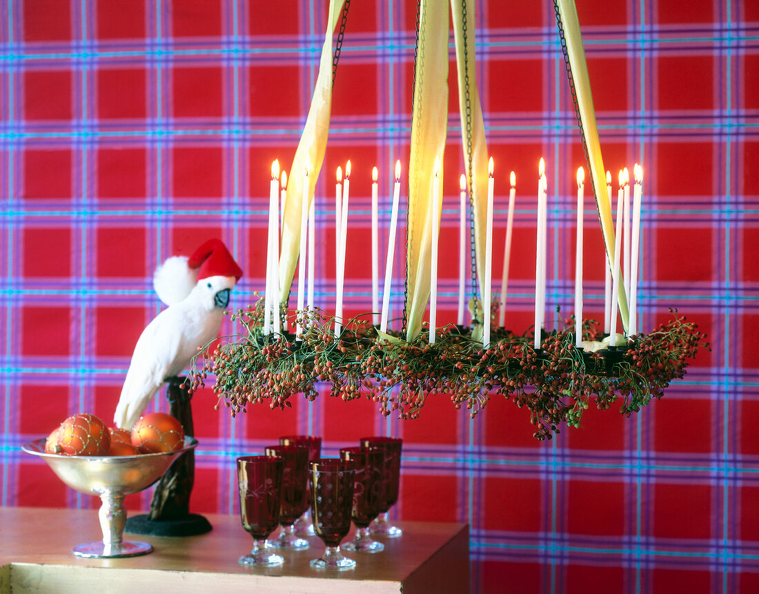 Metal chandelier decorated with cylindrical candles and multiflora berries