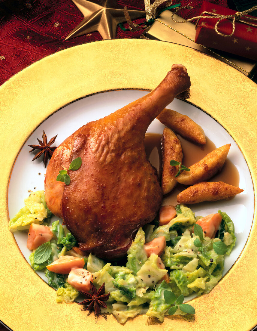 Fried goose leg with savoy and star anise on plate