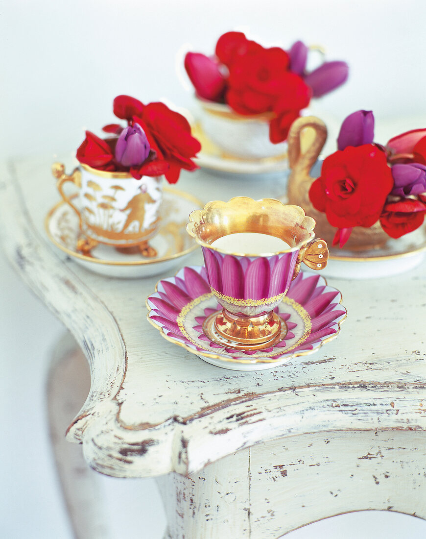 Floral printed cups with red begonias on table