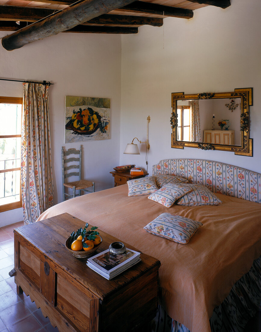 Rustic bedroom with beamed ceiling, wooden chest and tiles