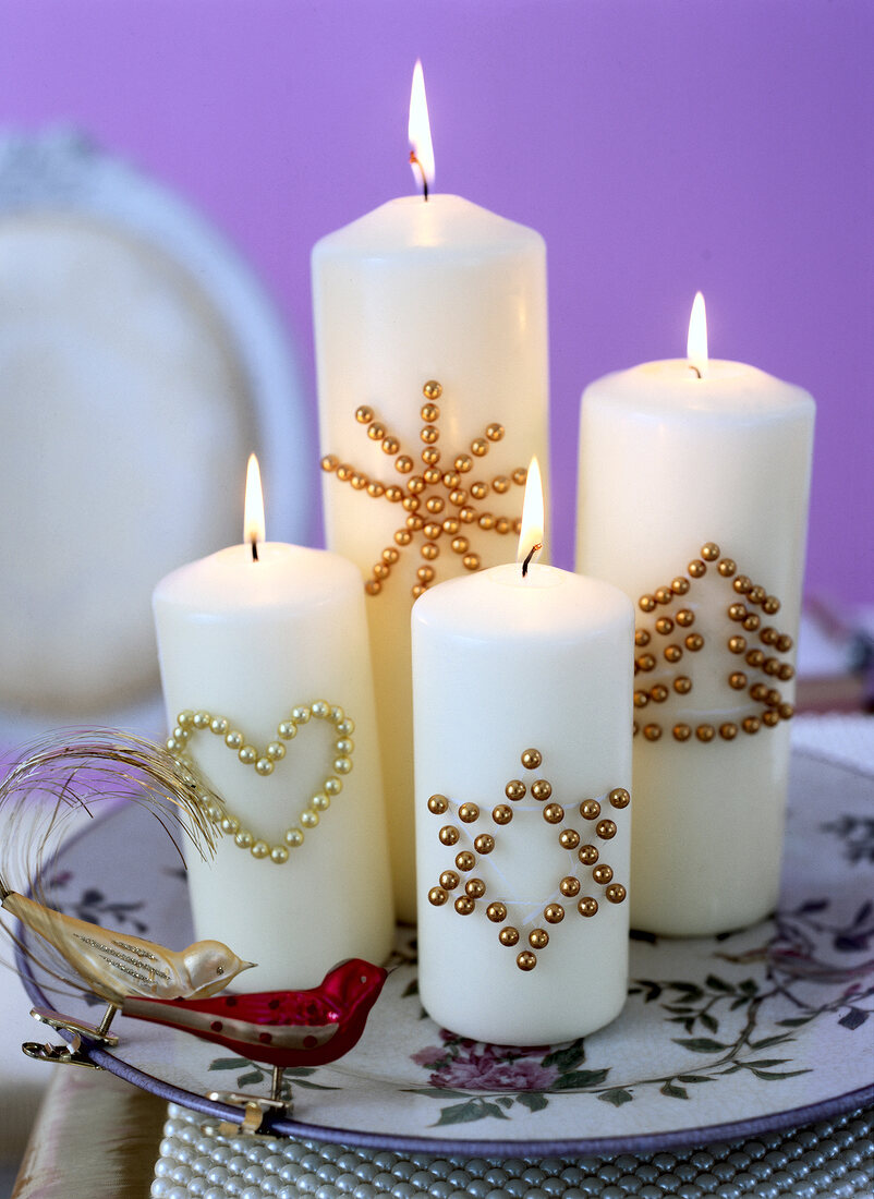 Close-up of lit white candles and Christmas decoration on plate
