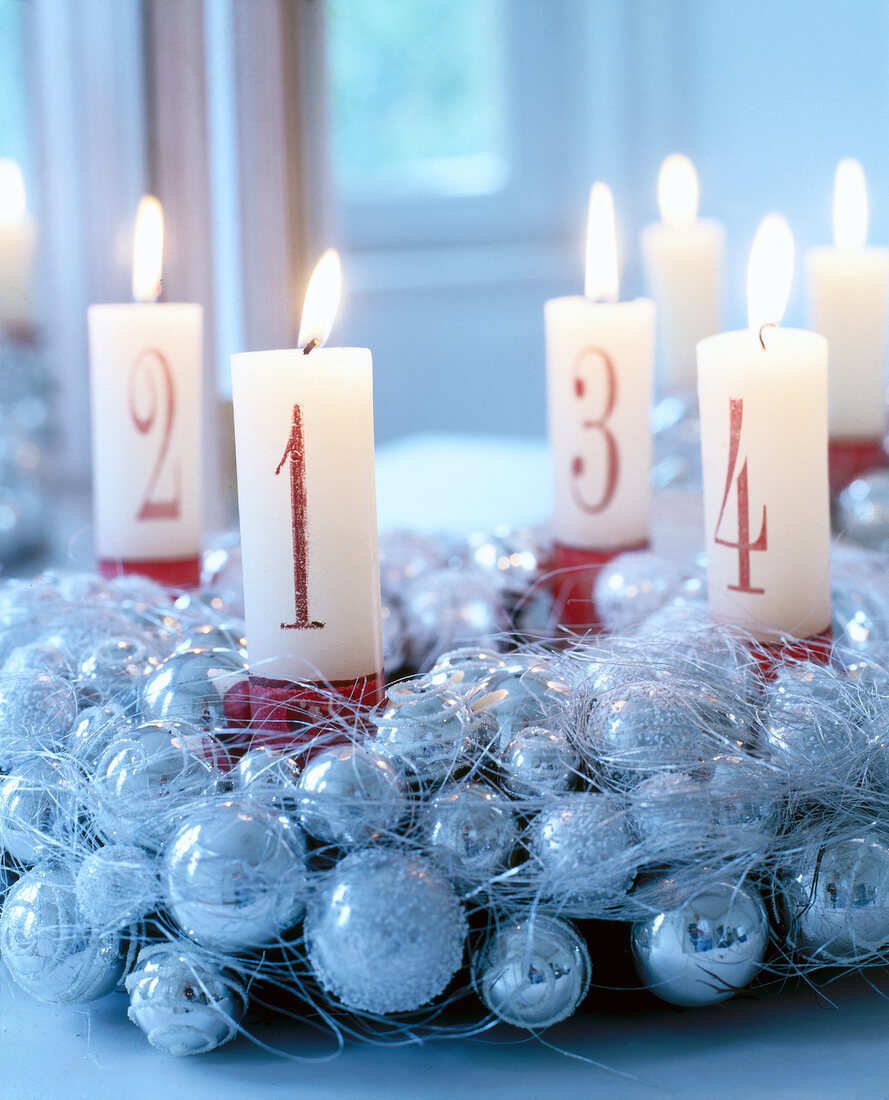 Christmas decoration with sliver baubles and lit candle with numbers