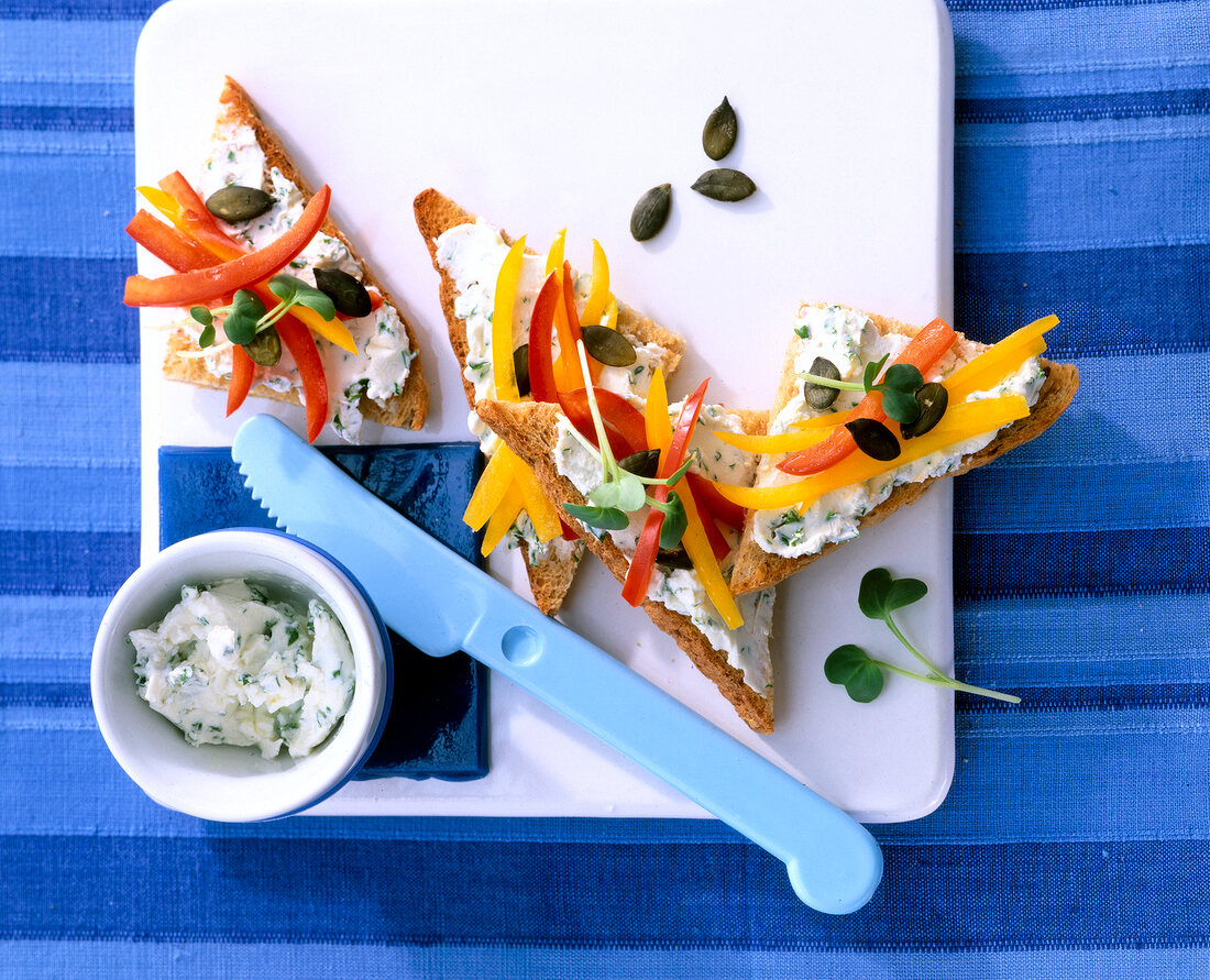 Toast topped with cream cheese, herbs and pepper on chopping board