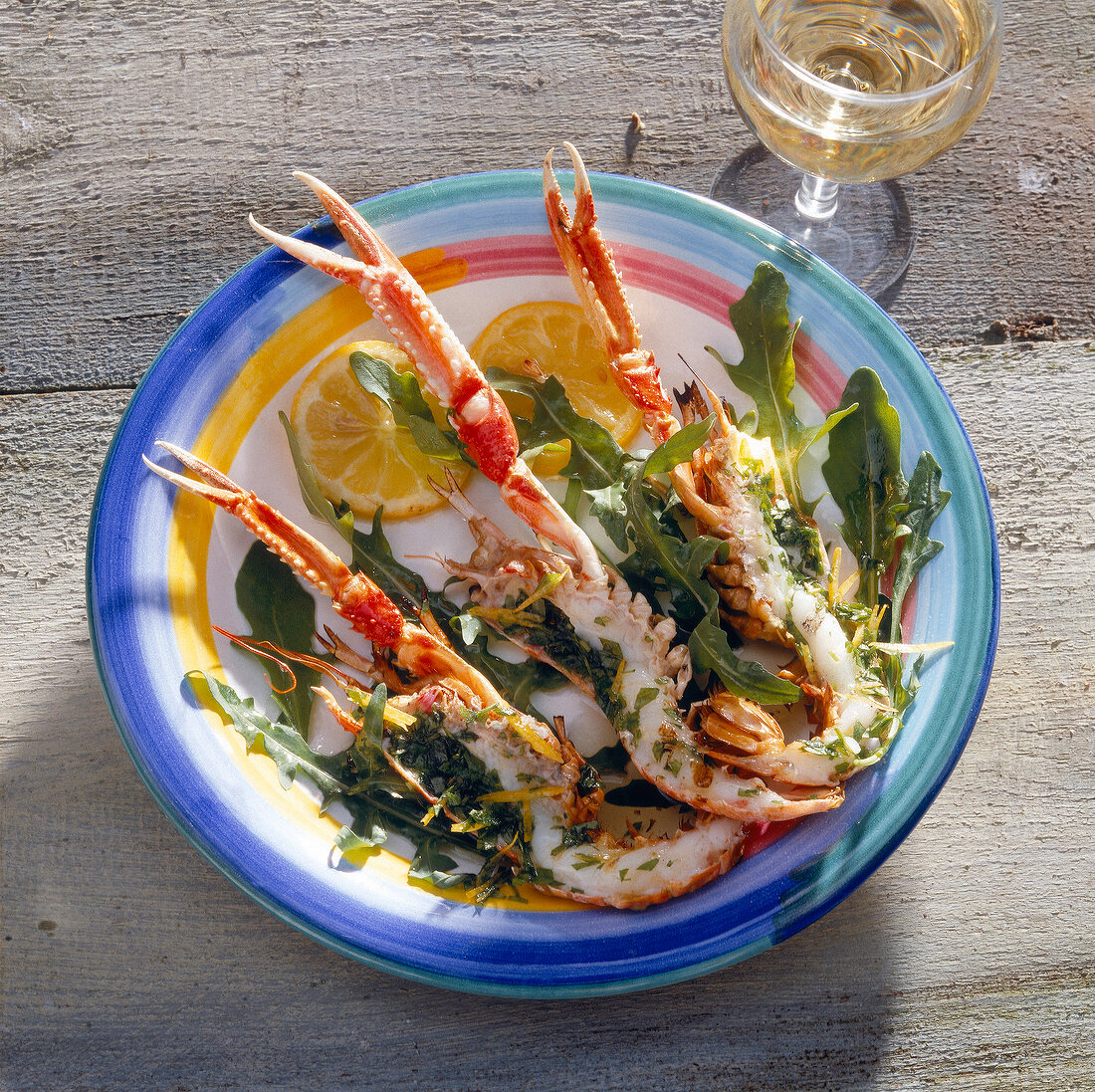 Grilled scampi with lemon on plate beside vinaigrette