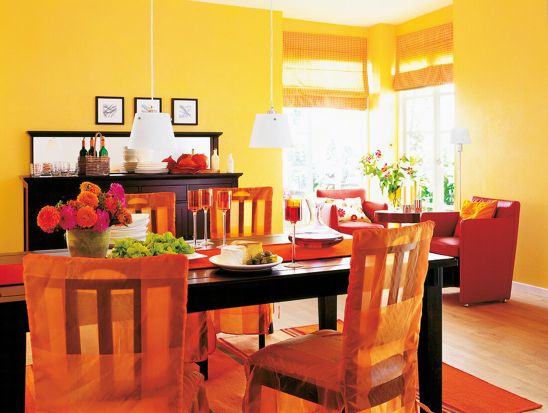 Esszimmer in Rot, Gelb und Orange: dunkle Holzmöbel, Stühle mit Hussen