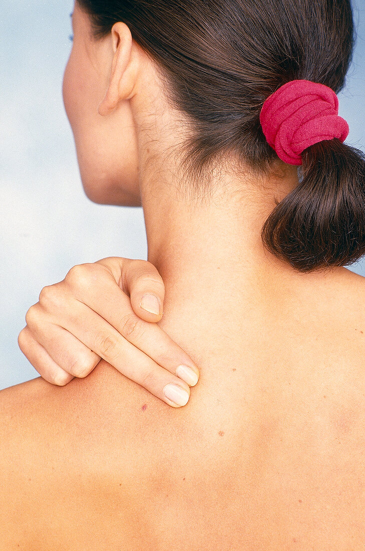 Rear view of woman performing acupressure for shoulder and neck pain