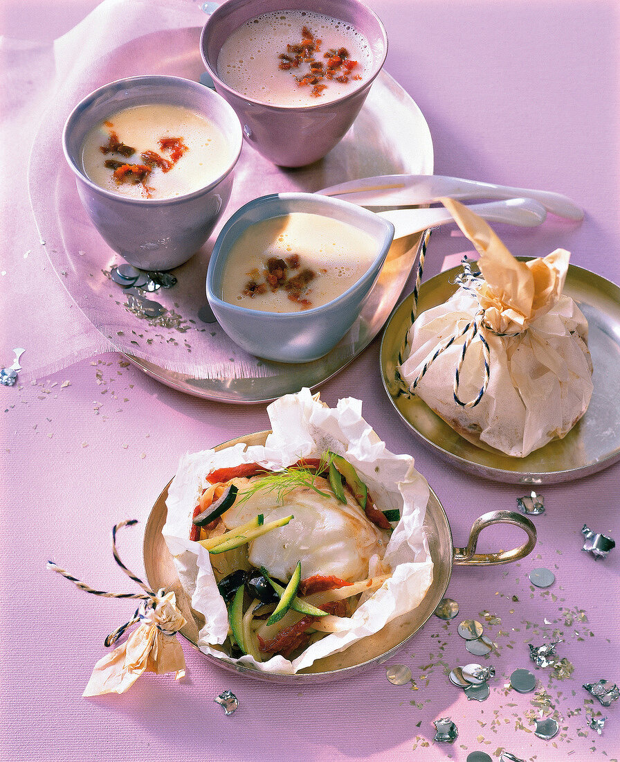 Fish with vegetables in parchment and white bean soup in small bowls