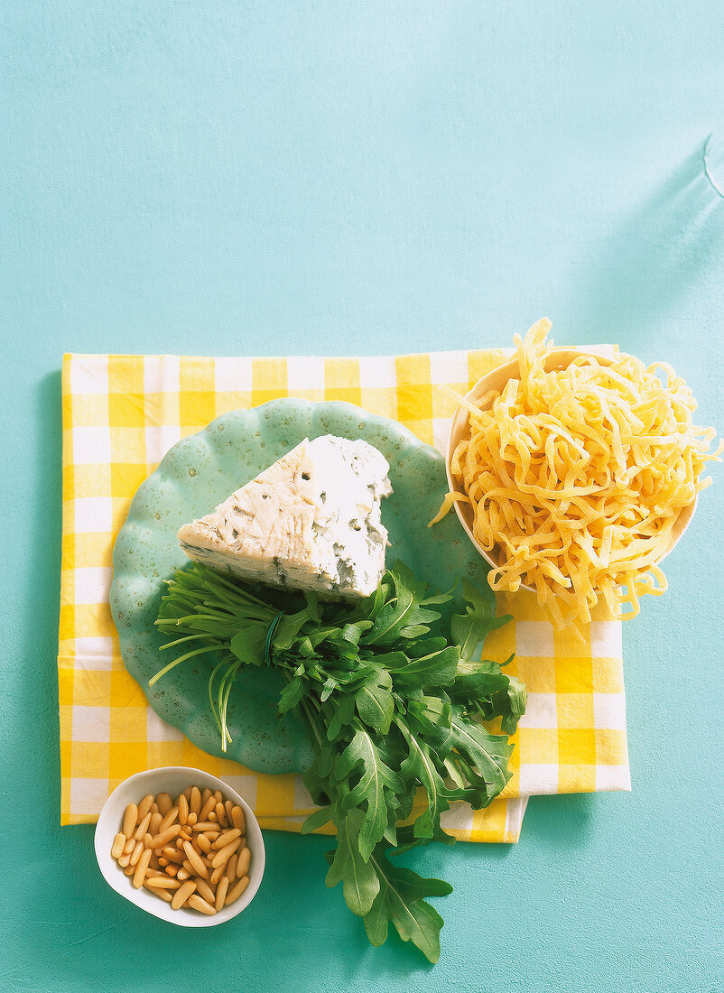 Arugula, tagliatelle, gorgonzola cheese and pine nuts on checked table cloth
