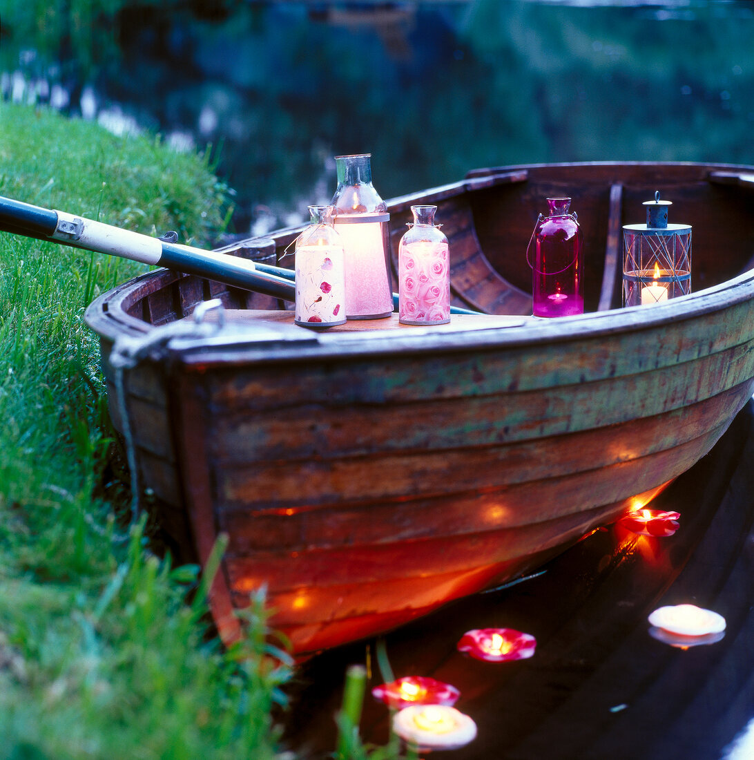 Various lanterns in boat and tea light floating on water