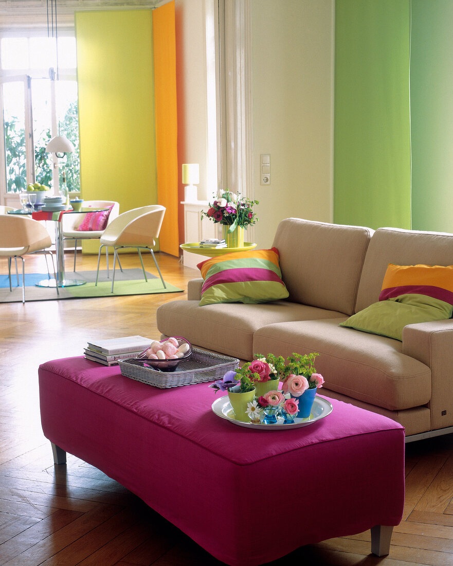 View of living room with colourful pillows on sofa and purple foot rest
