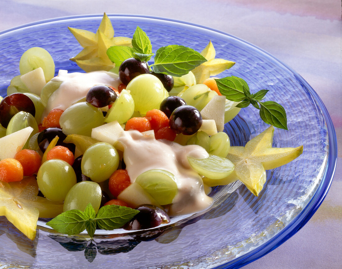 Fruit salad of green and blue grapes with yoghurt on blue dish