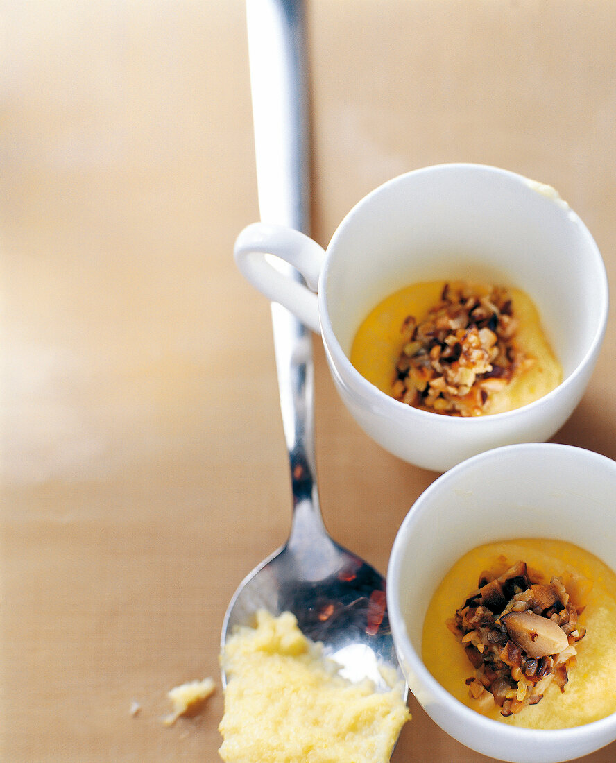 Two cups with Polentateig, beside a silver spoon batter it