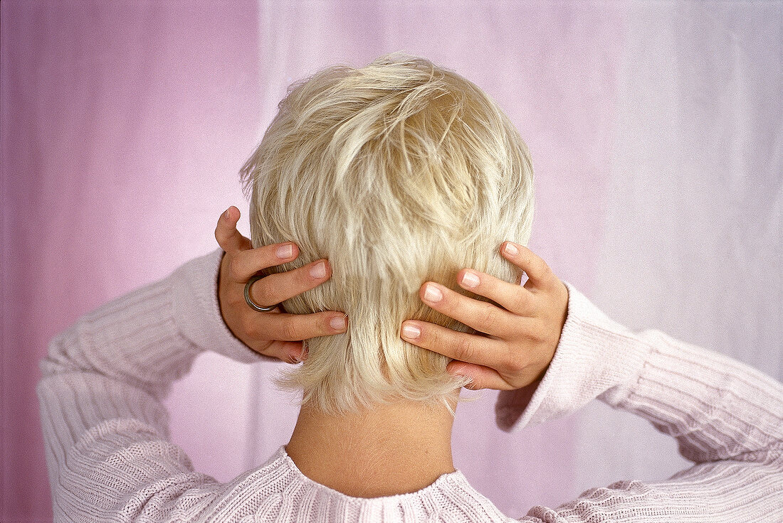 Rear view of blonde woman with short hair massaging her head