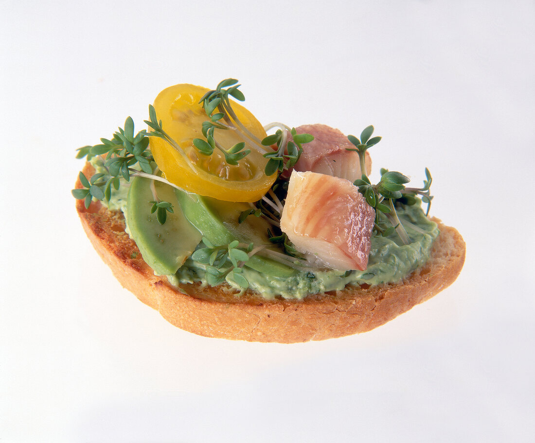 Close-up of baguette with avocado, mayonnaise, eel fillet and cress on white background