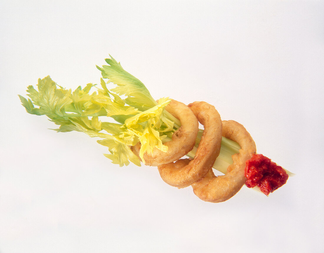 Close-up of squid rings with celery, peppers and vegetable paste on white background