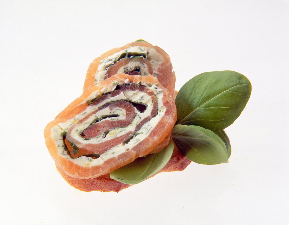 Close-up of salmon rolls with cream cheese on baguette slices on white background