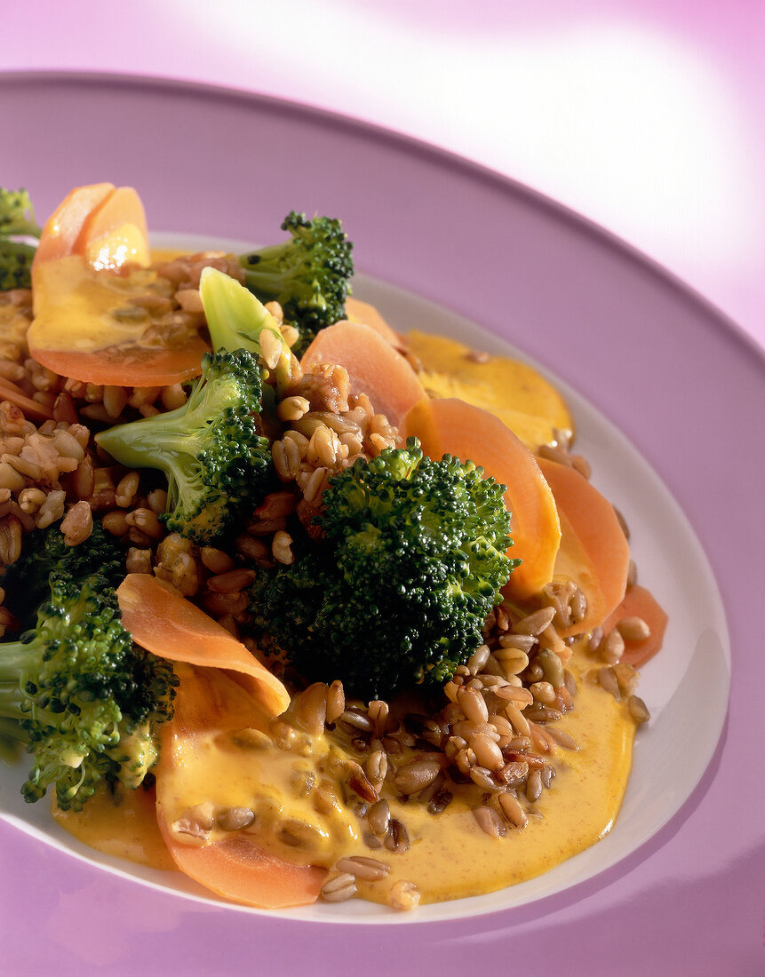 Close-up of green core with carrots and broccoli on pink plate