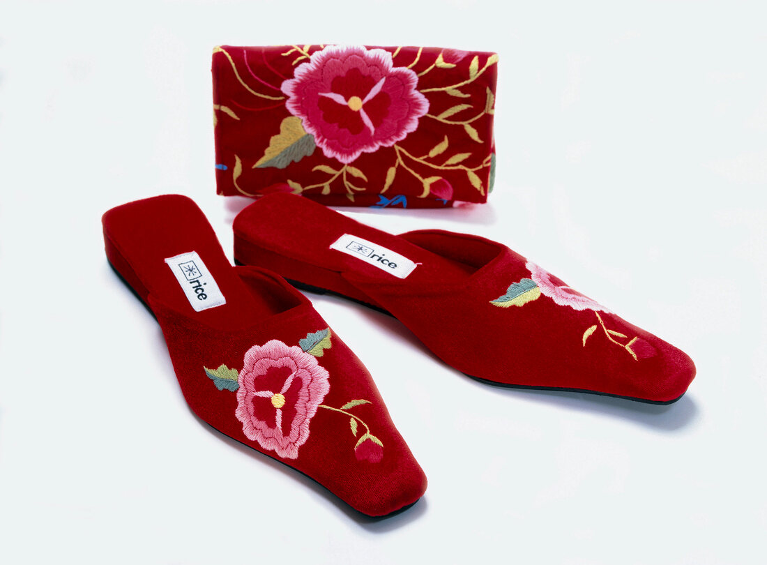 Floral embroidered velvet slippers and purse on white background