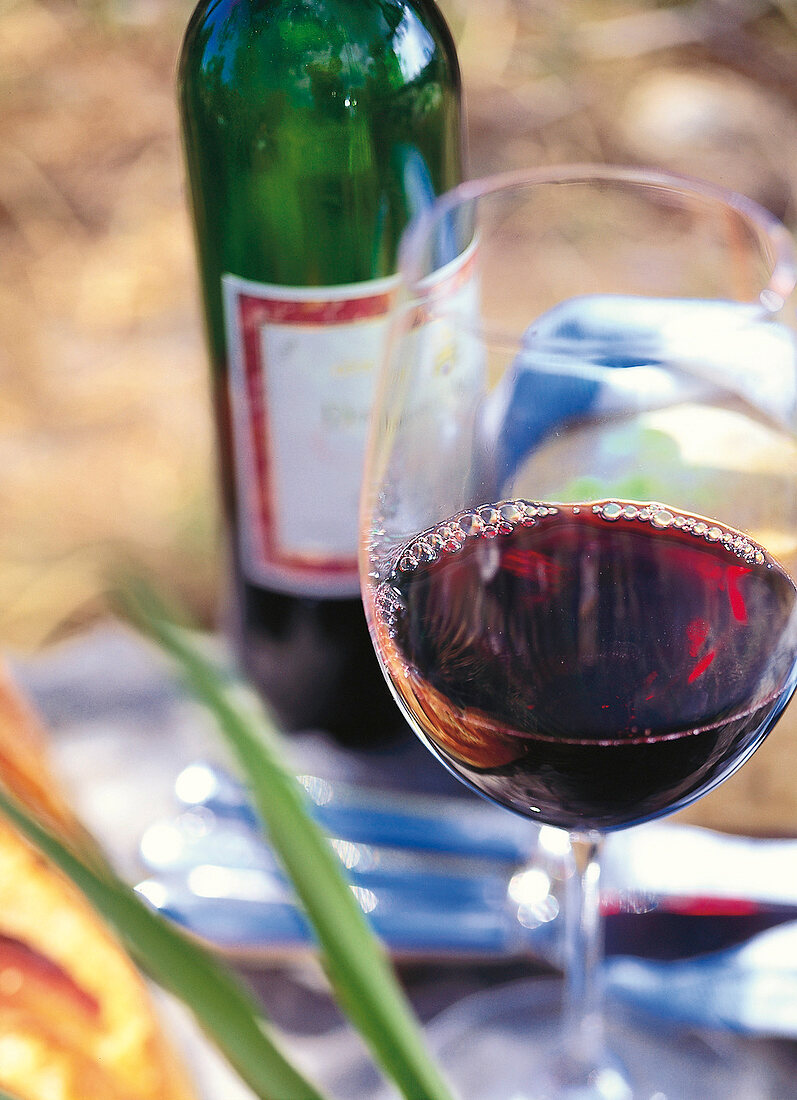 Rotwein - Glas mit Flasche daneben 