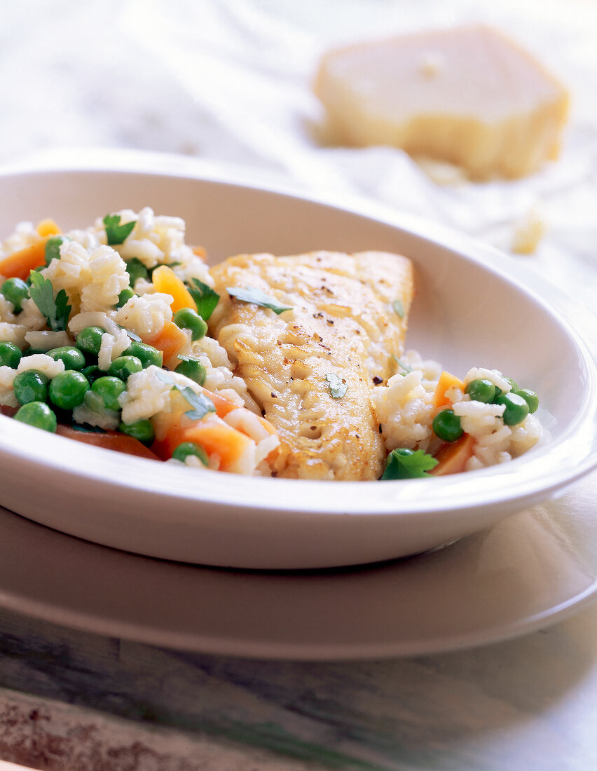 Close-up of fish with rice, carrots and peas on plate