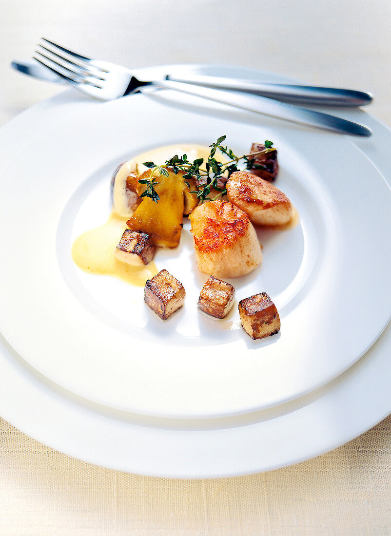 Scallops with geese and liver stuffing and hollandaise sauce on plate