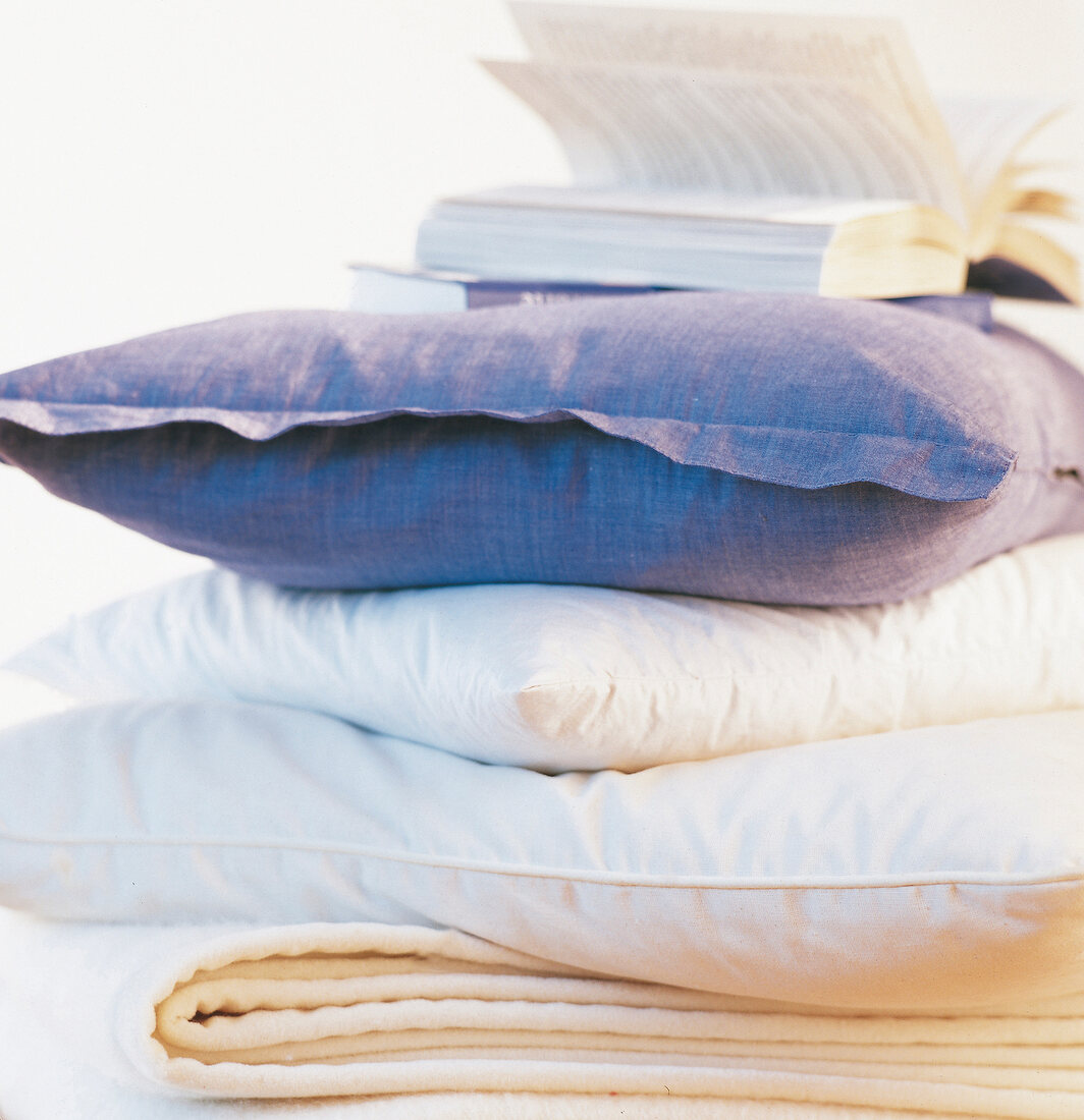 Close-up of several cushion placed one above other with book on top