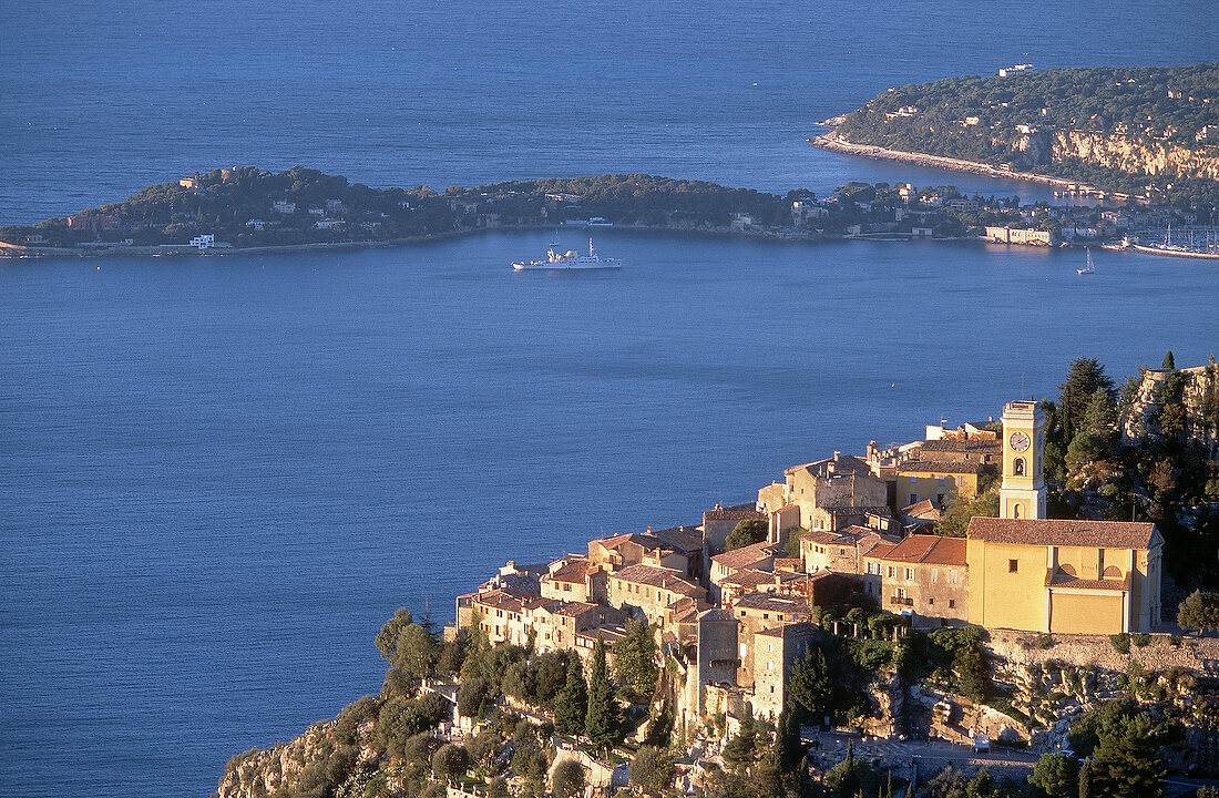 View of small town with sea and trees at dusk in Eze, France