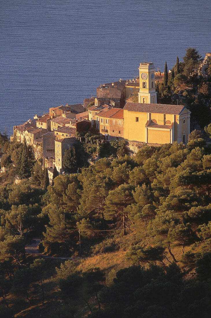 View of small town with sea and trees at dusk in Eze, France