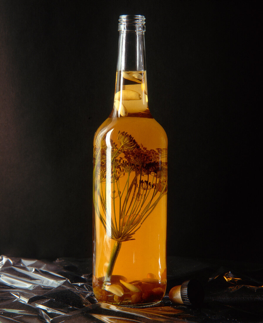 Dill flowers, almonds and raisins with cognac vinegar in glass bottle