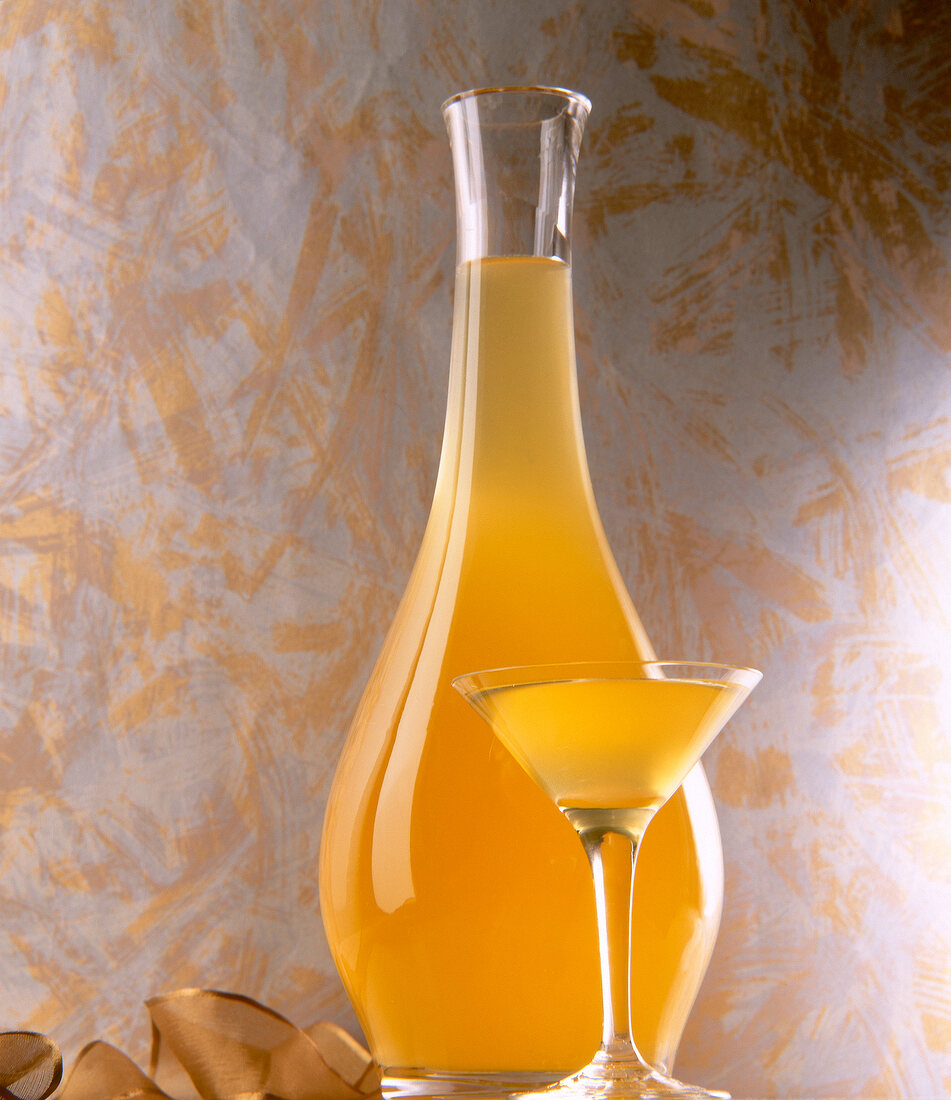 Bulbous glass bottle and martini glass with melon liqueur