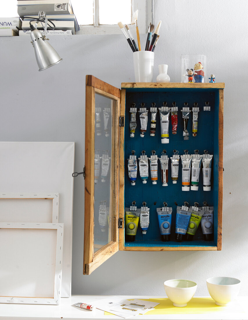 Canvases and a wooden wall cupboard for storing paint tubes
