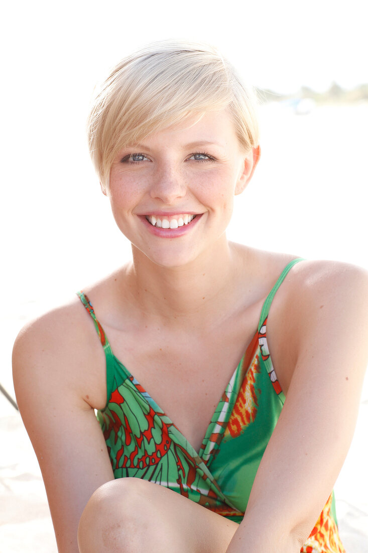 Blonde Frau mit kurzen Haaren im grünen Kleid am Strand