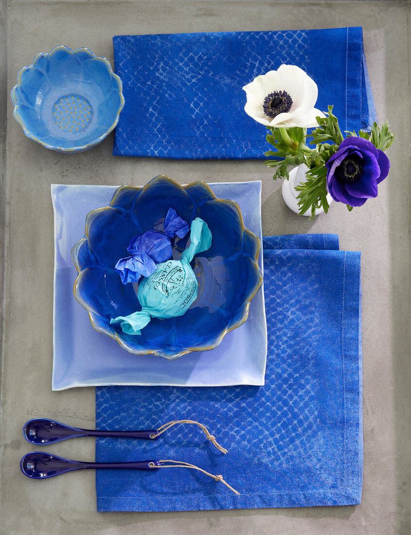 Two blue chocolates in bowl on table with napkins
