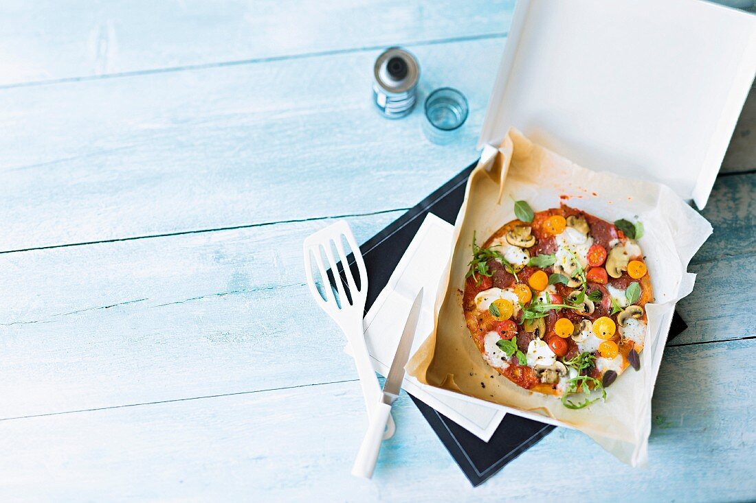 Wholemeal tomato-mozzarella pizza in a box (seen from above)