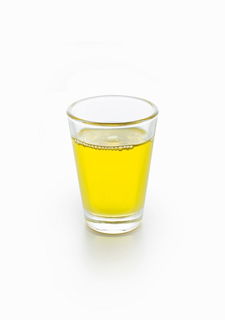 A glass of moringa oil on a white surface