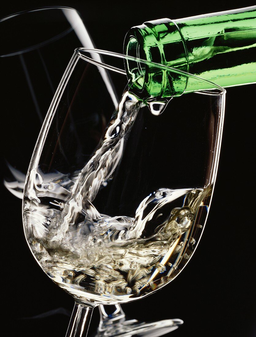 Weißwein aus grüner Flasche ins Glas einschenken